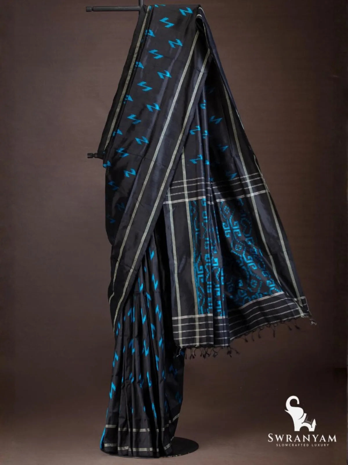 Black ikat silk saree with blue zigzag motifs, silver stripes and black pallu with blue geometric ikat panel and tassels