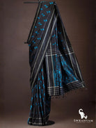 Black ikat silk saree with blue zigzag motifs, silver stripes and black pallu with blue geometric ikat panel and tassels