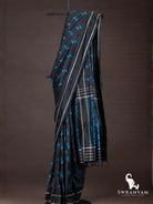 Black Pochampally ikat silk saree with blue Z-shaped ikat motifs and silver striped border draped on stand