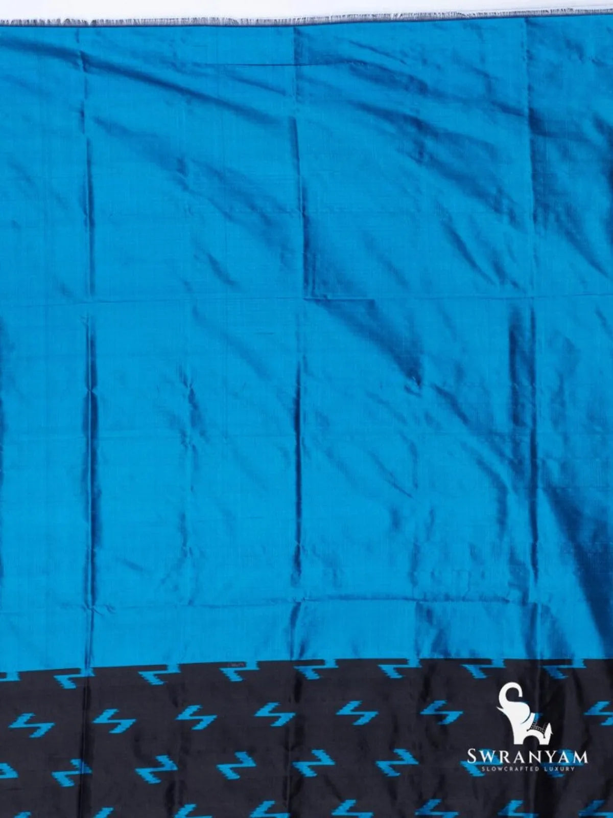 Plain bright blue silk section with black edge band of blue Z-shaped ikat motifs, part of the black Pochampally ikat saree
