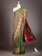 Bottle green Pochampally ikat silk saree with maroon pallu and tassels flowing, shown on mannequin