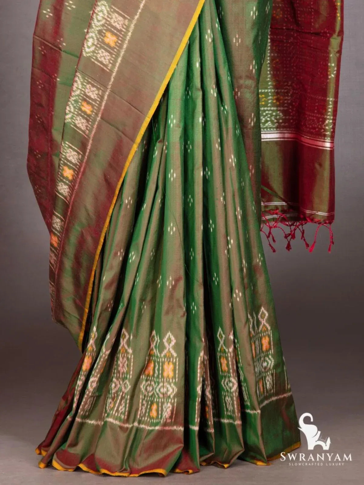 Bottle green Pochampally ikat saree pleats with ikat motif hem and maroon pallu with red tassels