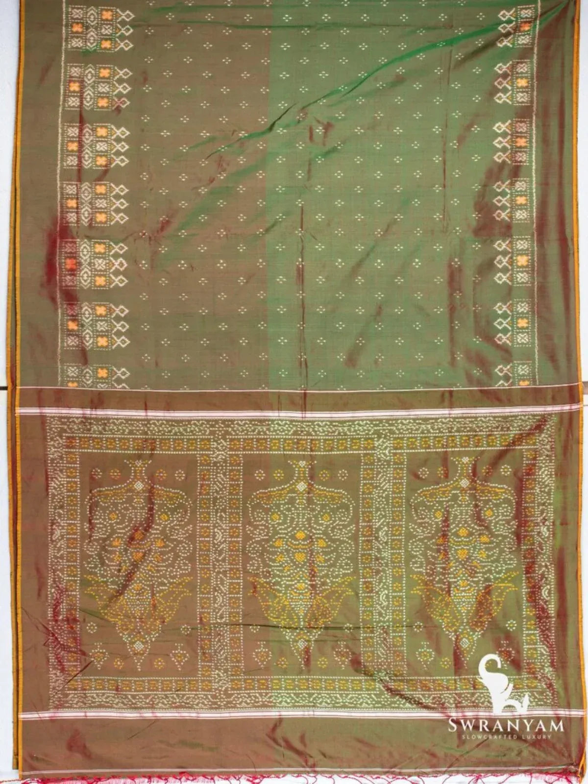 Pochampally ikat silk saree spread flat showing bottle green body, ikat borders and dotted motif pallu