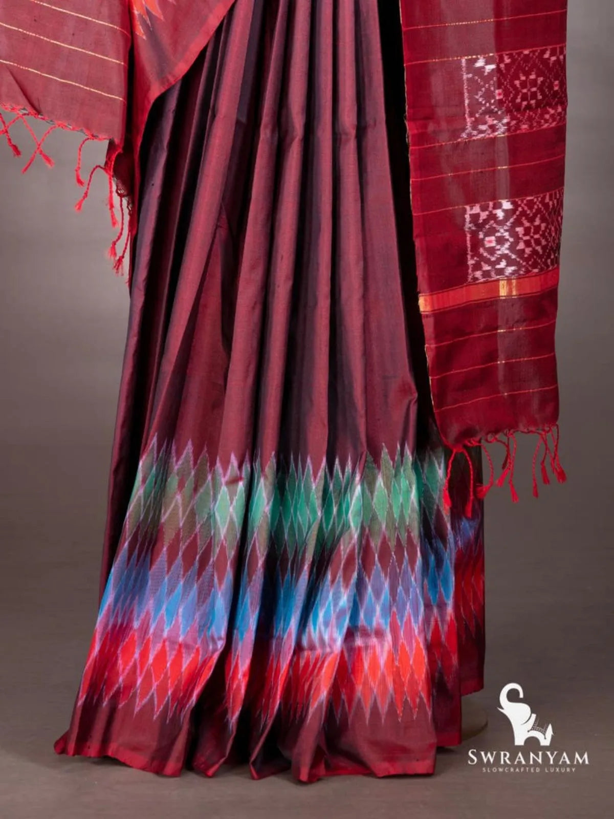 Maroon ikat silk saree pleats with multicolour diamond ikat hem band in red, blue and green, and pallu with zari stripes
