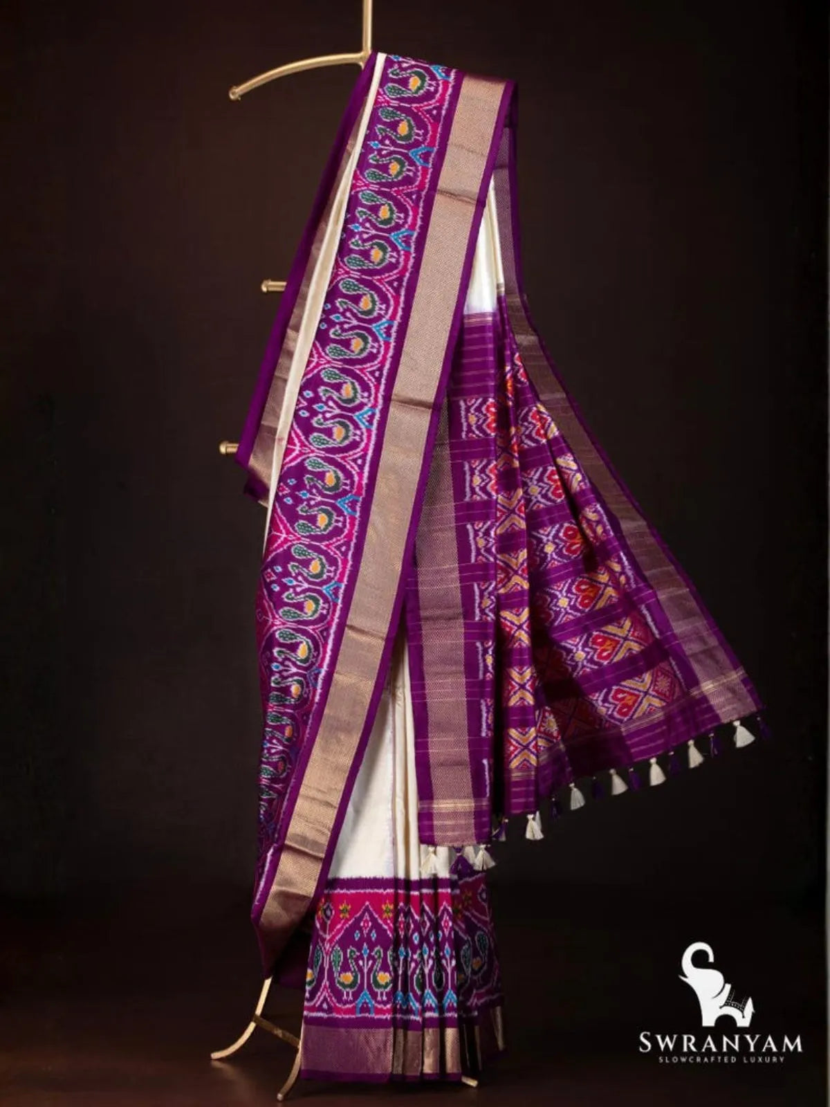 Ivory Pochampally ikat silk saree with royal purple peacock ikat border, gold zari band and purple pallu on hanger