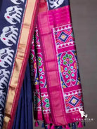 Close-up of pink pallu with multicolour geometric and floral ikat motifs, gold zari border and tassels on navy blue saree