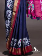 Navy blue ikat silk saree pleats with white elephant motif hem, gold zari border with maroon edging and pink pallu