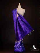 Back view of royal purple and peach tussar silk ikat saree showing purple pallu with ikat bands, woven stripes and tassels