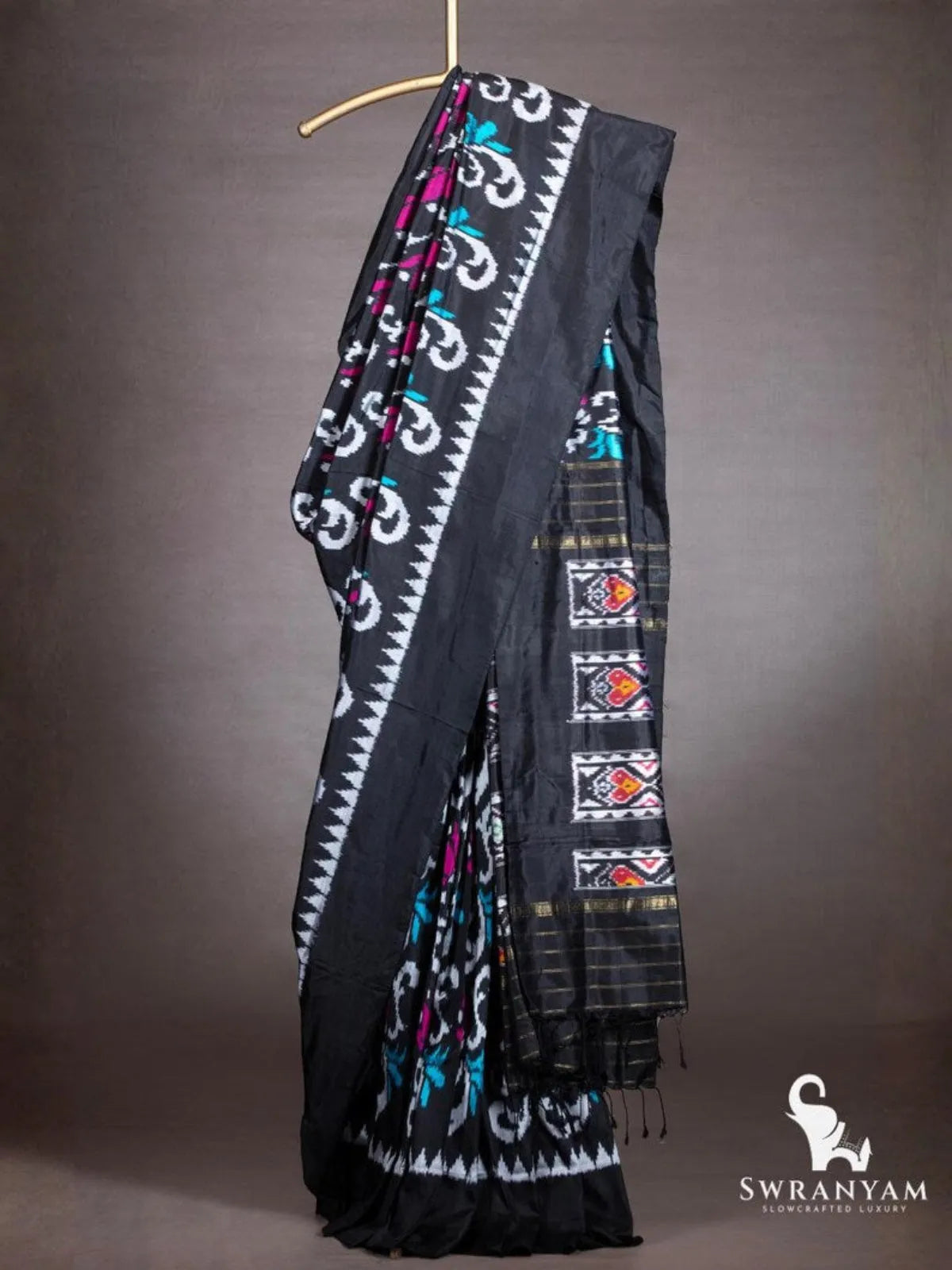 Black Pochampally ikat silk saree with white scroll motifs, magenta and teal accents and white temple border on hanger