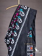 Close-up of black ikat silk saree shoulder drape with white scroll motifs, magenta and teal accents and temple border