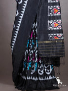 Black ikat silk saree pleats with white scroll motifs and teal accents, black pallu with heart motif ikat panels
