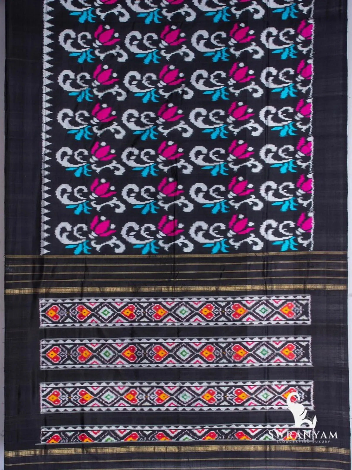 Black Pochampally ikat silk saree spread flat with white scroll and magenta tulip motifs and multicolour ikat pallu panels