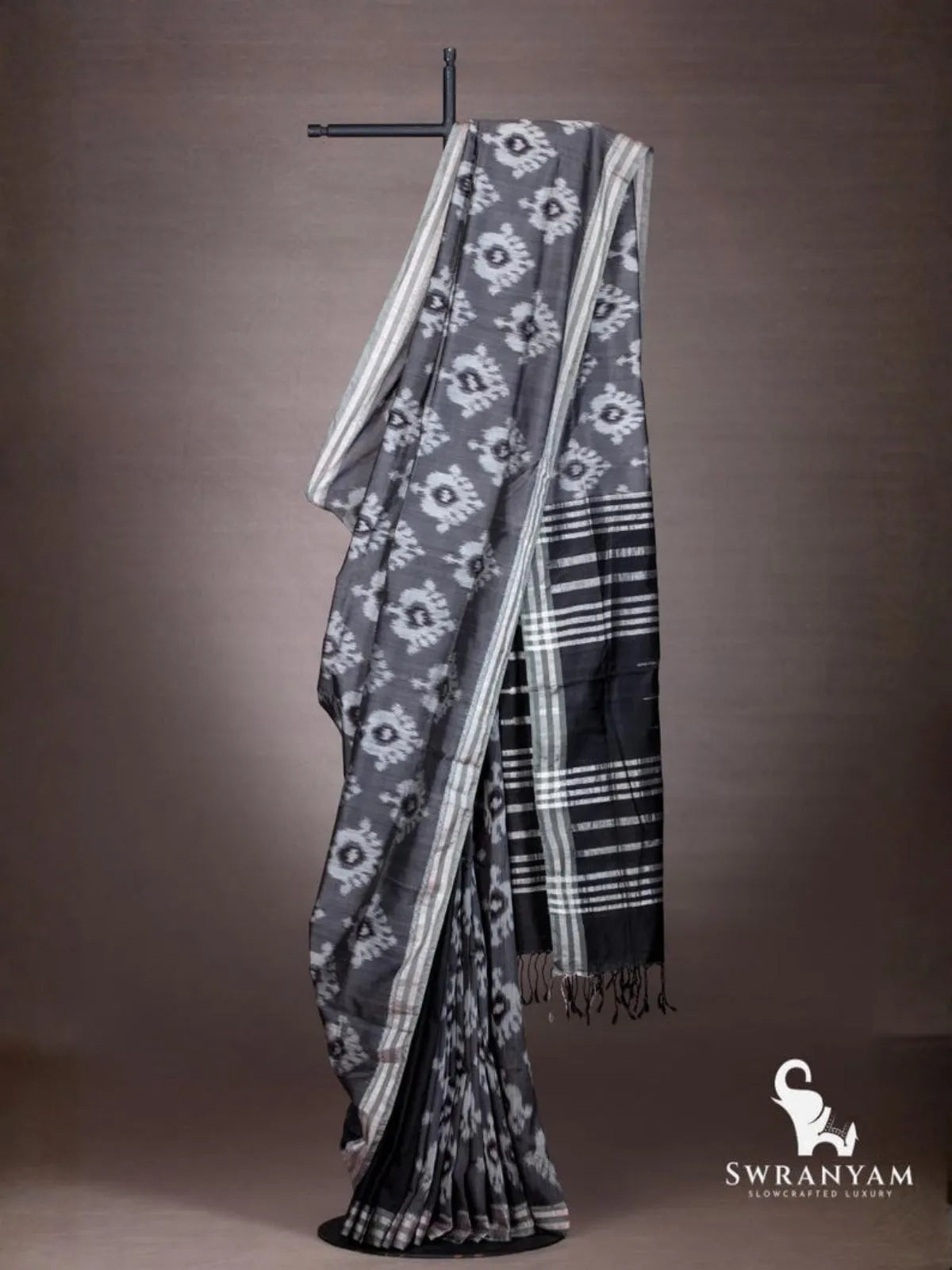 Charcoal grey Pochampally weft ikat cotton silk saree with white ikat motifs and black striped pallu draped on stand