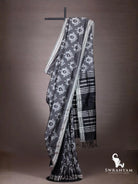 Charcoal grey Pochampally weft ikat cotton silk saree with white ikat motifs and black striped pallu draped on stand