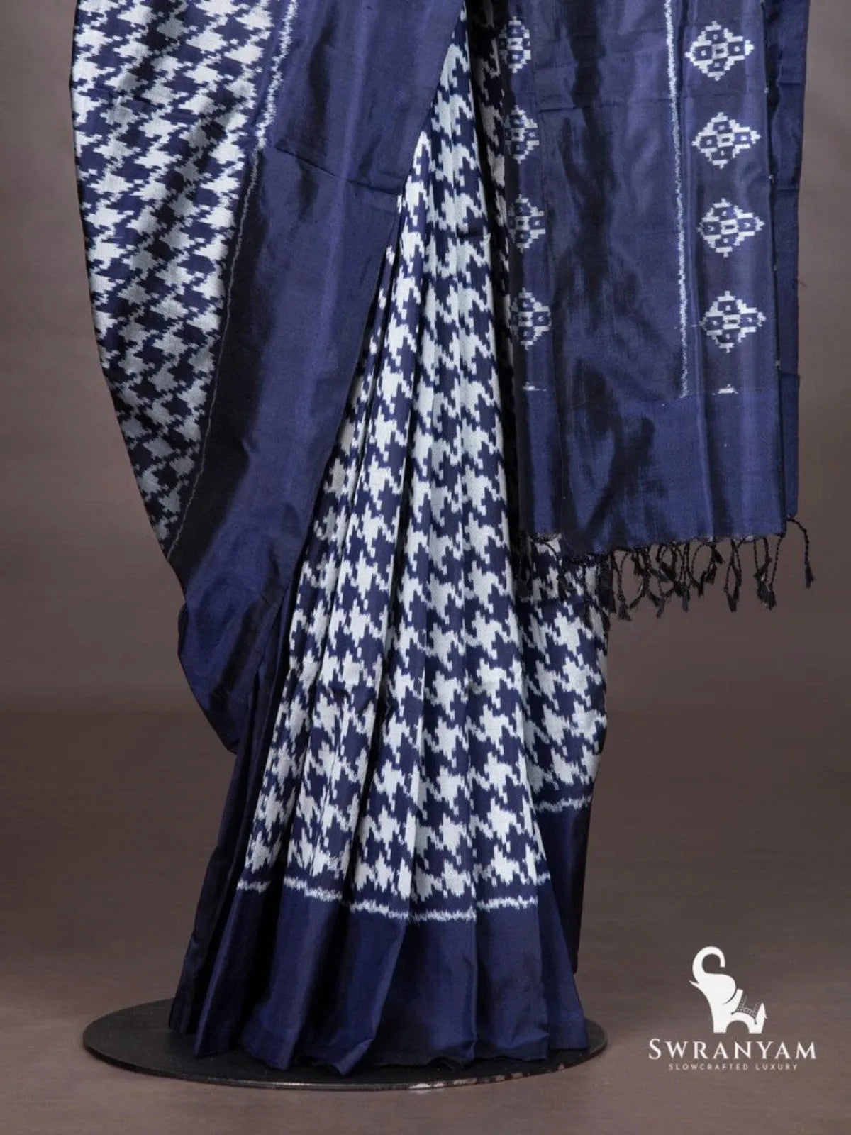 Indigo blue ikat silk saree pleats with houndstooth pattern, solid hem and diamond motif pallu with black tassels