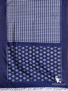 Indigo blue Pochampally ikat silk saree spread flat showing white houndstooth body and pallu with diamond ikat motifs