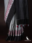 Close-up of tussar silk ikat saree pleats with red zigzag hem, black border and red and grey tassels