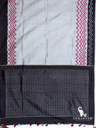 Charcoal grey tussar silk ikat saree spread flat showing red zigzag borders, black border and black patterned pallu