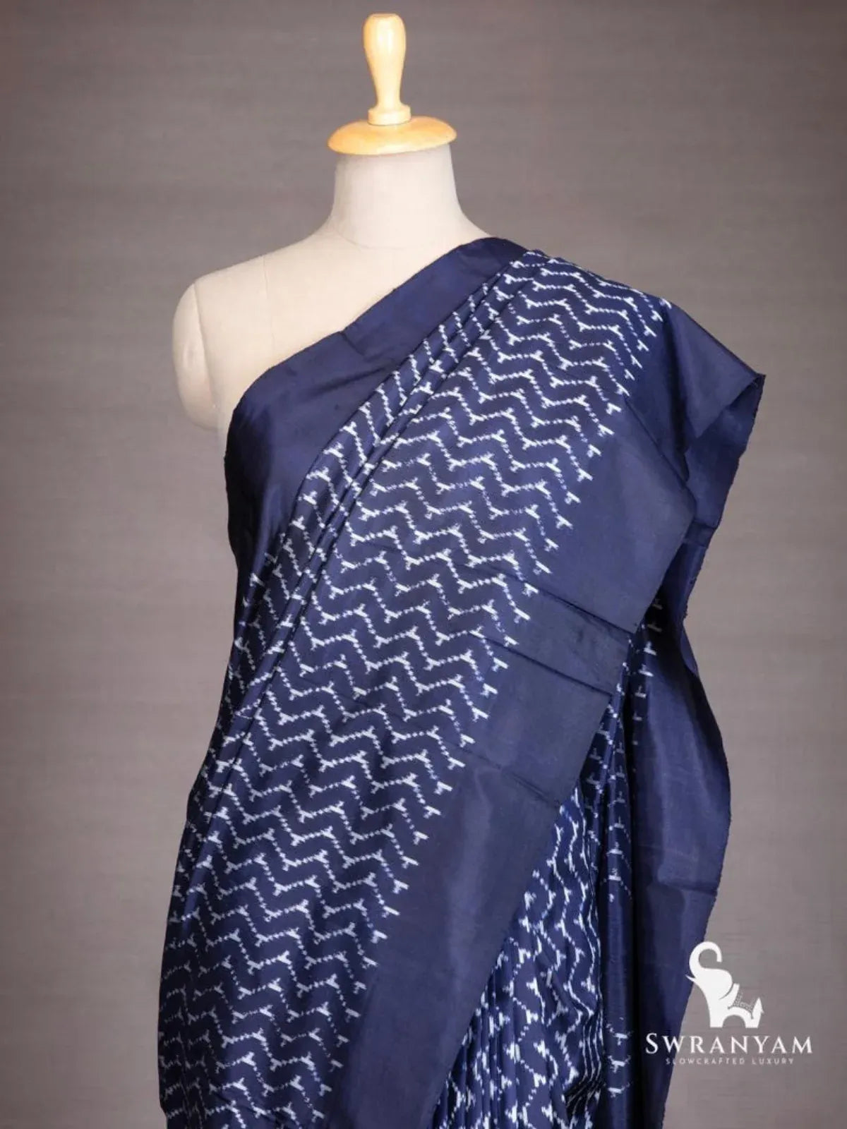 Close-up of white chevron ikat pattern on indigo blue silk saree shoulder drape with solid border