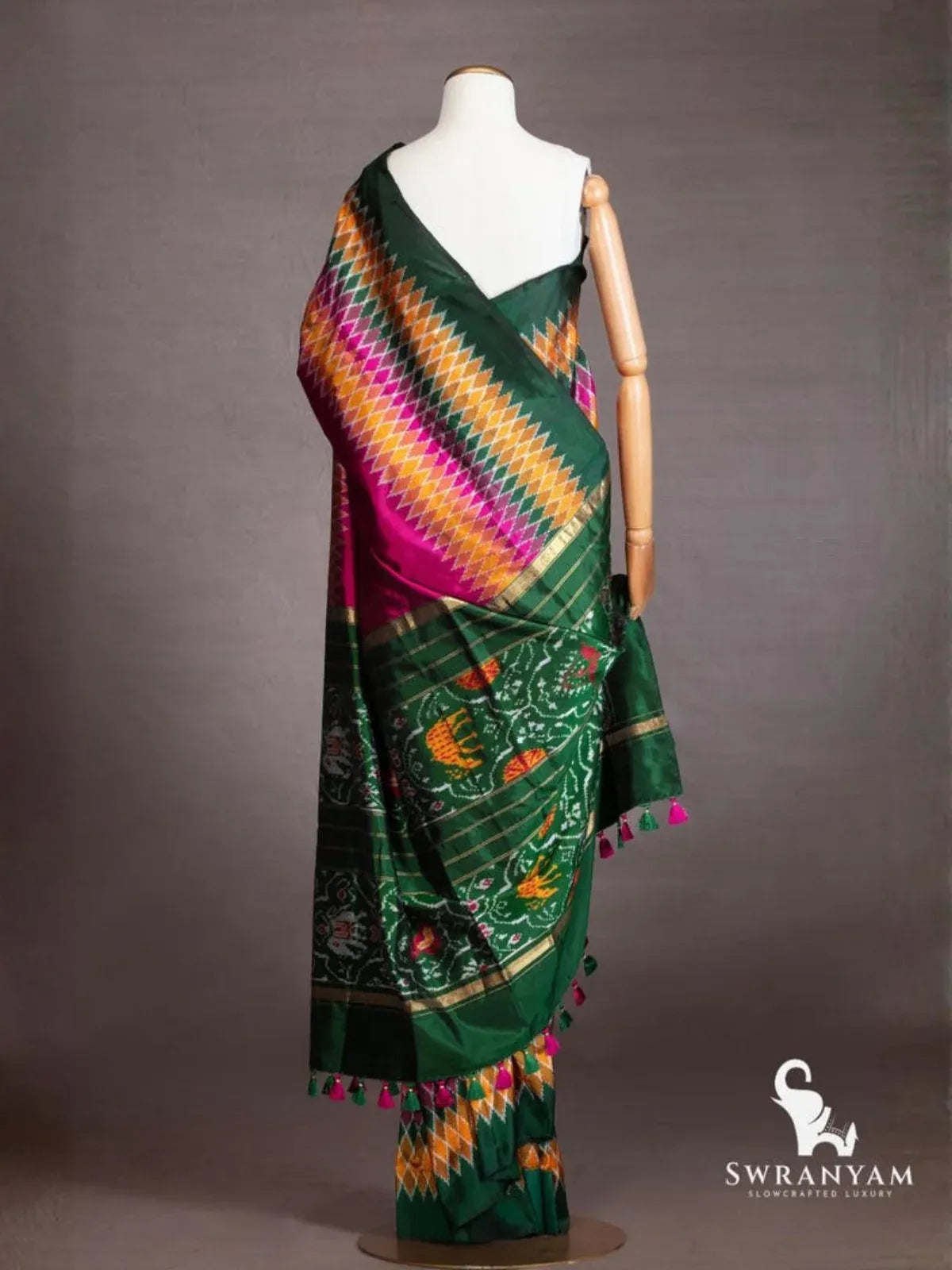 Back view of wine purple ikat silk saree showing emerald green pallu with woven animal motifs, zari stripes and tassels
