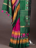 Wine purple ikat silk saree pleats with diamond ikat hem and emerald green pallu with zari stripes and pink green tassels