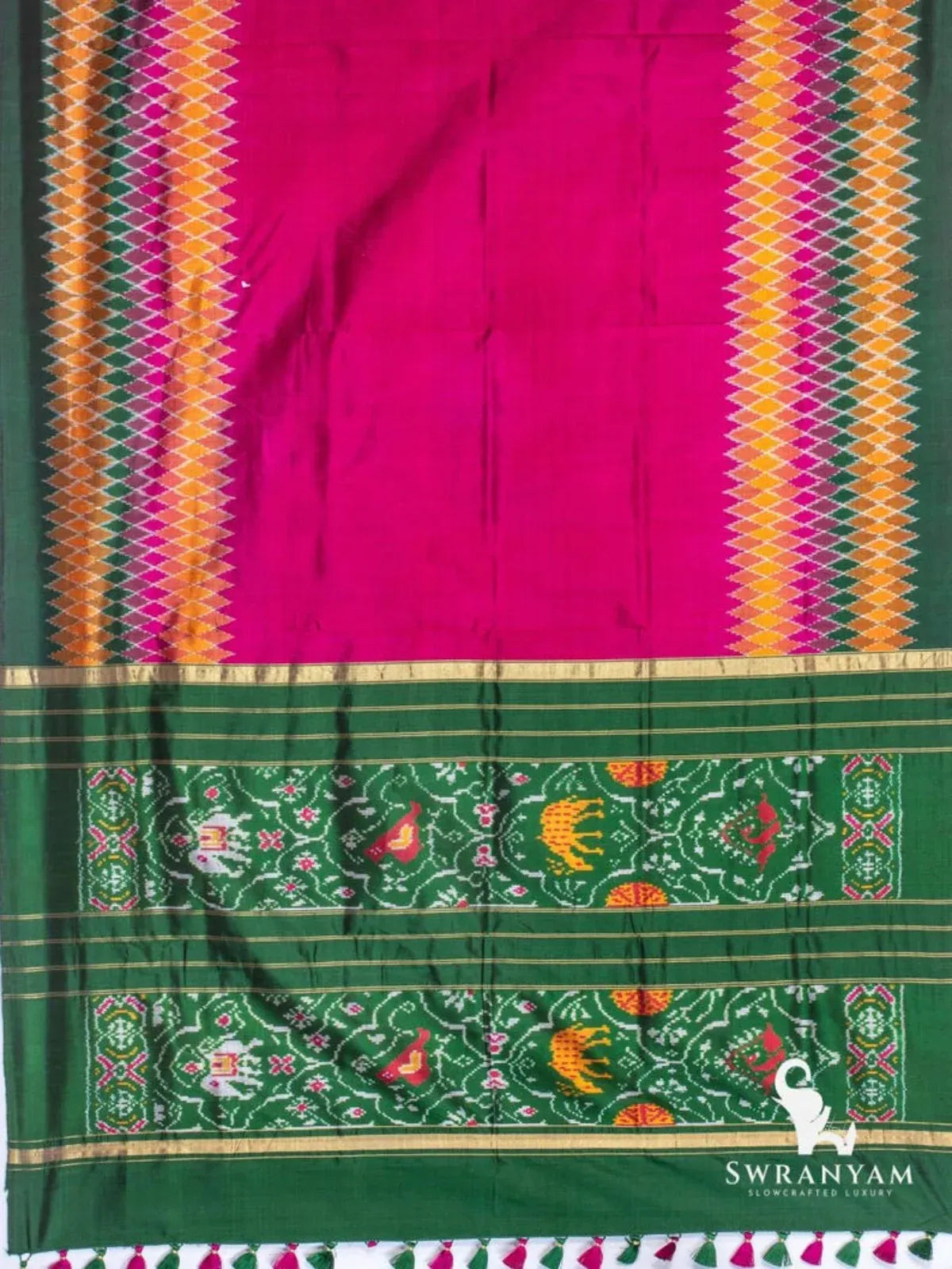 Wine purple ikat silk saree spread flat showing plain body, diamond ikat borders, green pallu with woven motifs and tassels