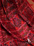 Close-up of red pallu of Pochampally ikat silk saree with maroon, orange and white woven ikat motifs
