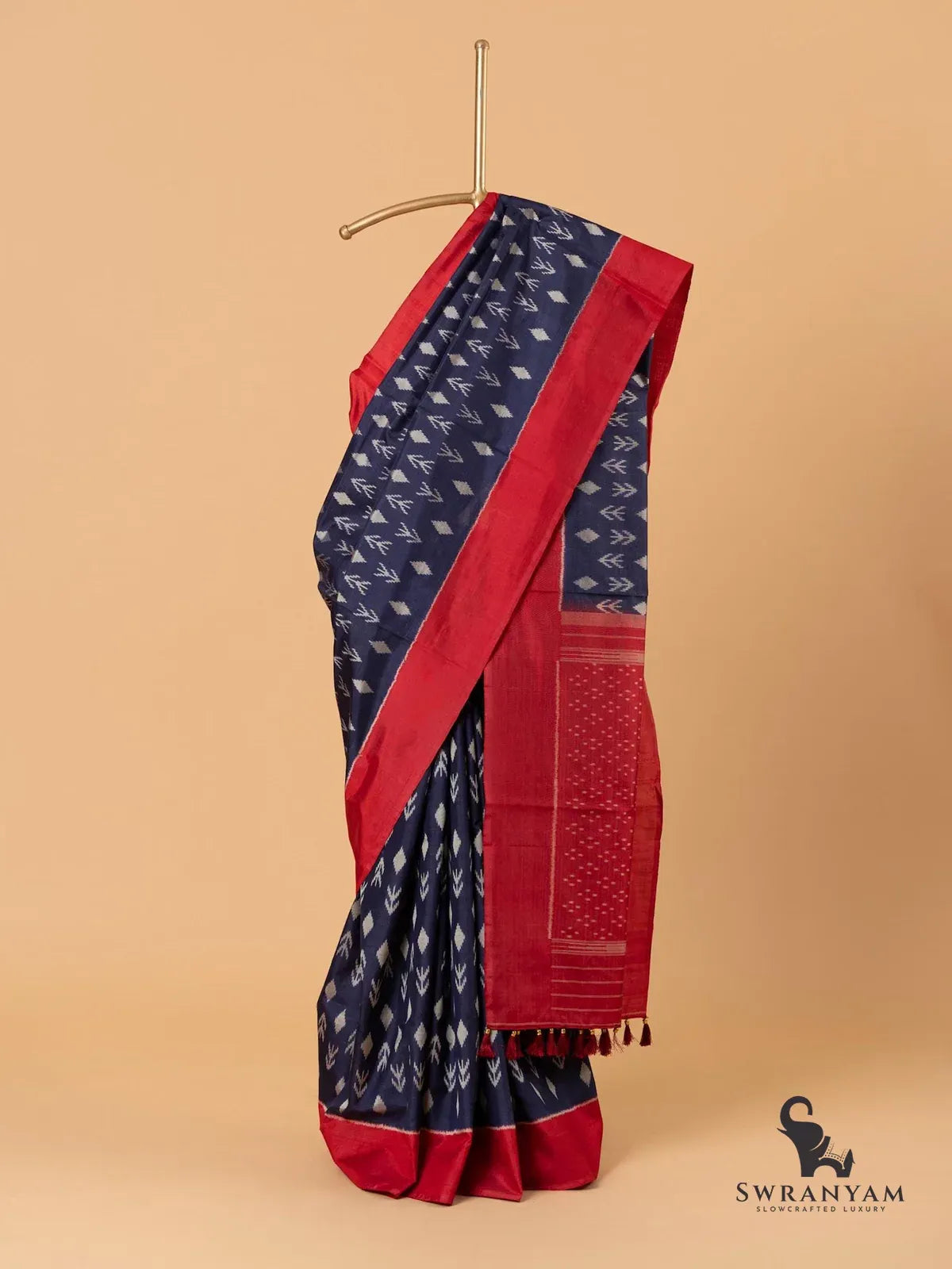 Navy blue Pochampally ikat silk saree with red border draped on stand, full front view with tasselled pallu