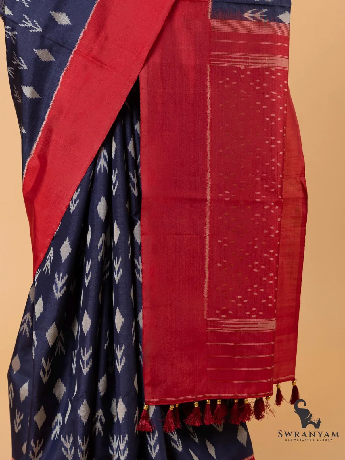 Red pallu of Pochampally ikat silk saree with woven ikat dots, striped ends and handmade silk tassels