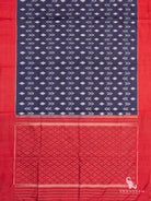 Navy blue Pochampally ikat silk saree spread flat showing white ikat body motifs, red borders and red dotted ikat pallu