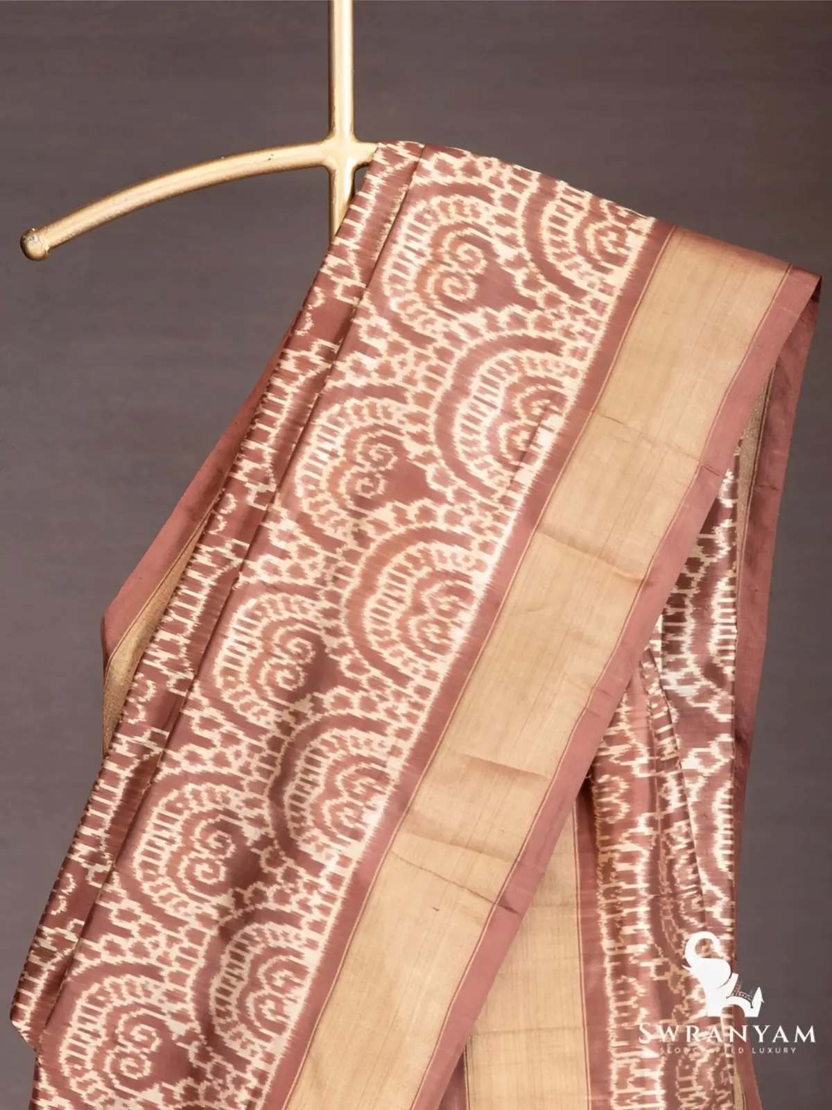 Close up of white scalloped swirl ikat motifs and antique gold border on cocoa brown silk saree pallu