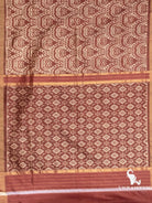 Flat lay of cocoa brown ikat silk saree showing swirl motif pallu and diamond ikat pattern with zari stripes