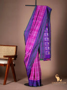 Pink Pochampally ikat silk saree with purple striped border and tasselled pallu draped on a stand