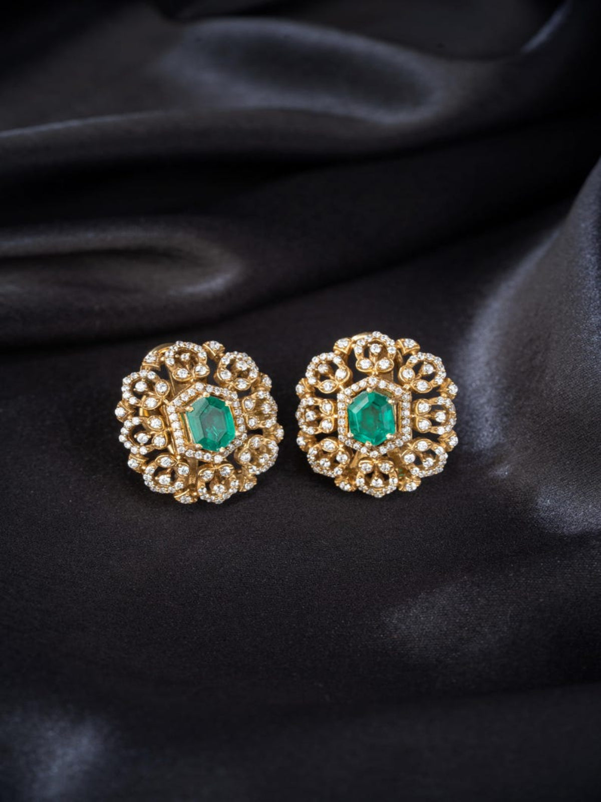 Swranyam 92.5 silver Victorian stud earrings with emerald stone, on black fabric background