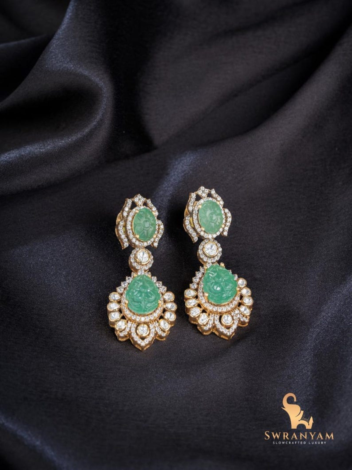 Swranyam 92.5 silver Moissanite Polki dangle earrings with carved emerald stone, on black fabric background
