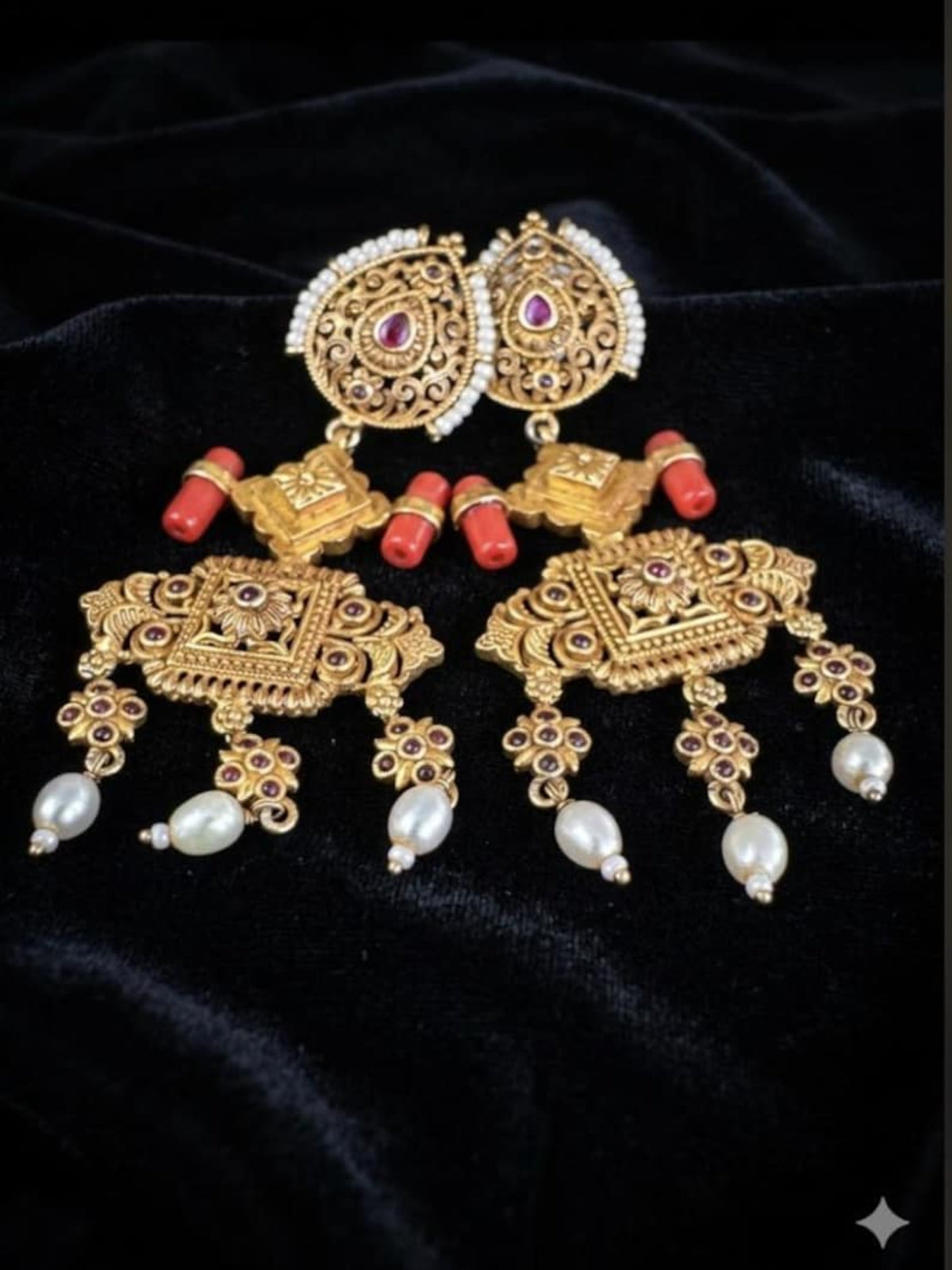 Close-up of Swranyam silver statement earrings showing carved gold-tone detail and coral stone