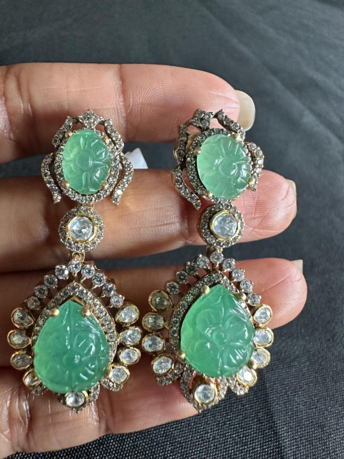 Swranyam silver Polki earrings held in hand for size reference