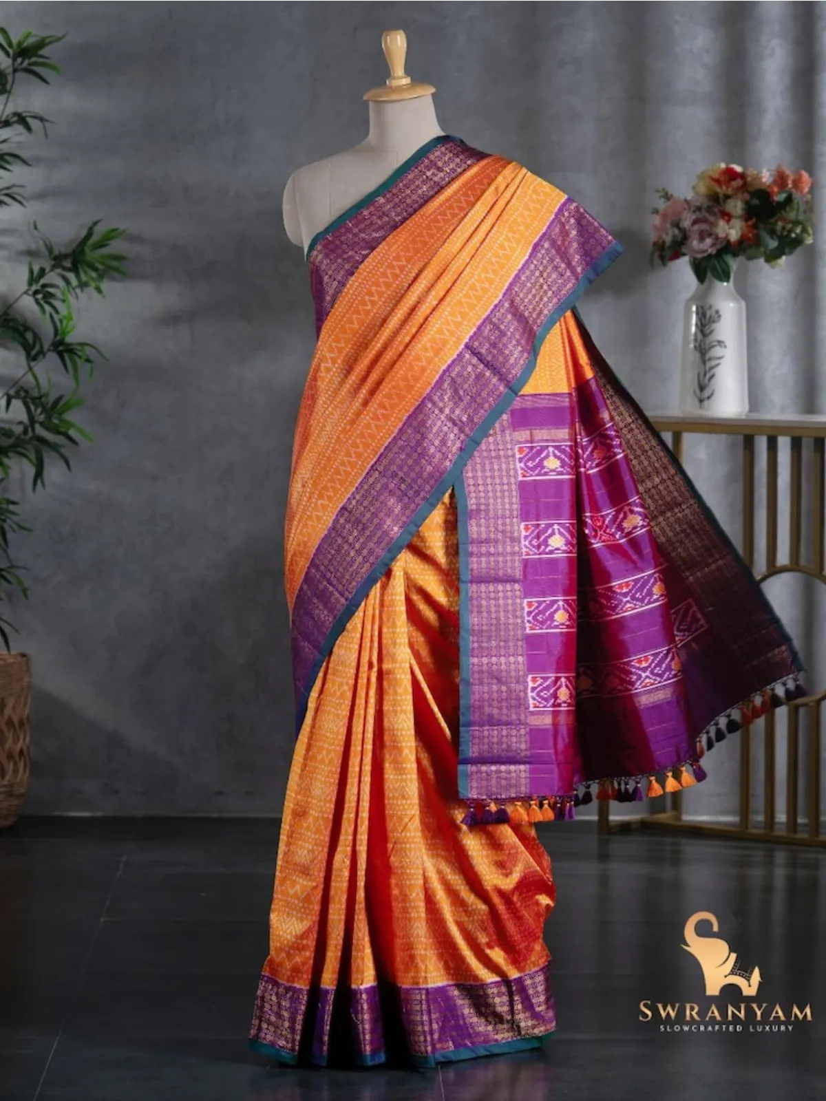 Full drape of pure orange twill ikat silk saree with flowing purple ikat pallu and orange purple tassels